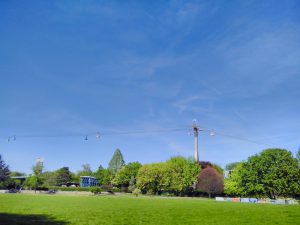 Sunny lawns, trees and a cable car crossing the picture