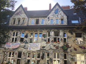 Grey building with insects painted onto it and banners hanging from the windows