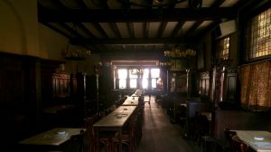 Traditional dark wood beer hall interior with a central long table, at Brauerei Paeffgen, Cologne