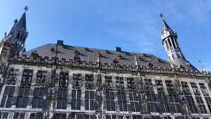 Aachen Town hall looking at the roof with statues and a blue sky